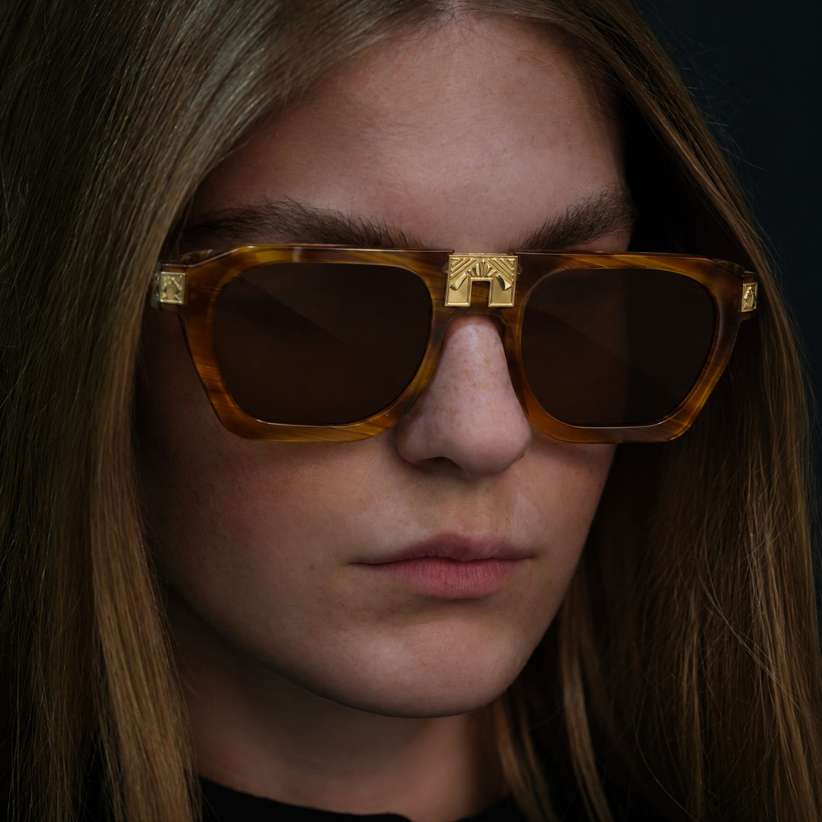 Model wearing ARIA NOIR Ahava sunglasses in Caramel Stripe honey amber striped acetate with gold bridge detail