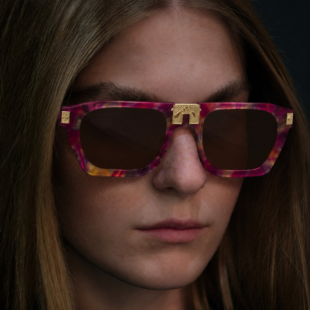 Model wearing ARIA NOIR Ahava sunglasses in Tutti Frutti pink and magenta acetate with gold bridge detail
