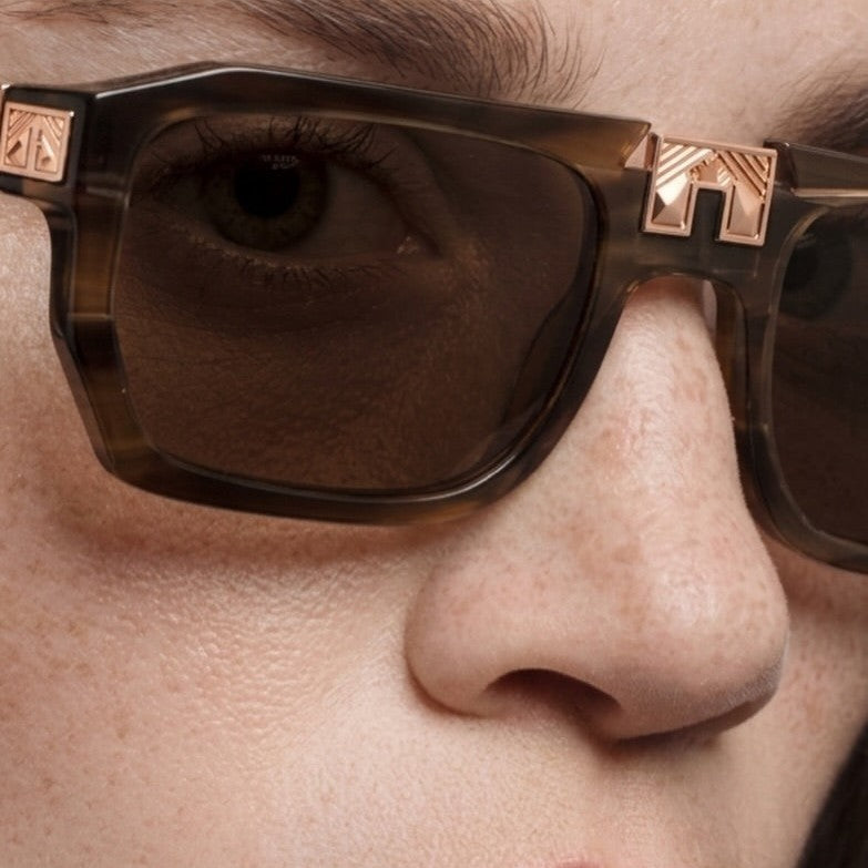Model wearing ARIA NOIR ARCA II sunglasses in Root Beer Float brown striped acetate with rose gold bridge detail