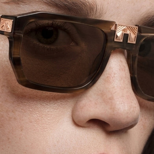 Model wearing ARIA NOIR ARCA II sunglasses in Root Beer Float brown striped acetate with rose gold bridge detail