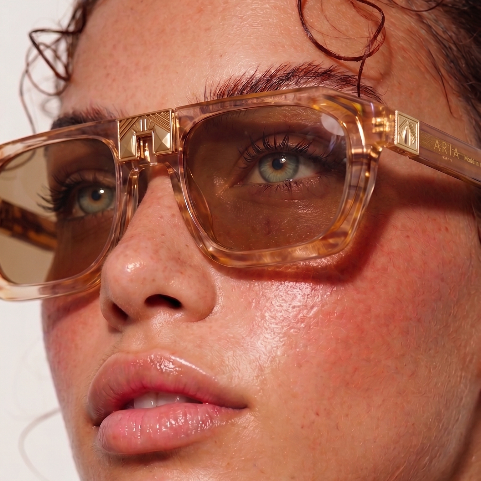 Close-up of a person wearing gold sunglasses with a blurred background